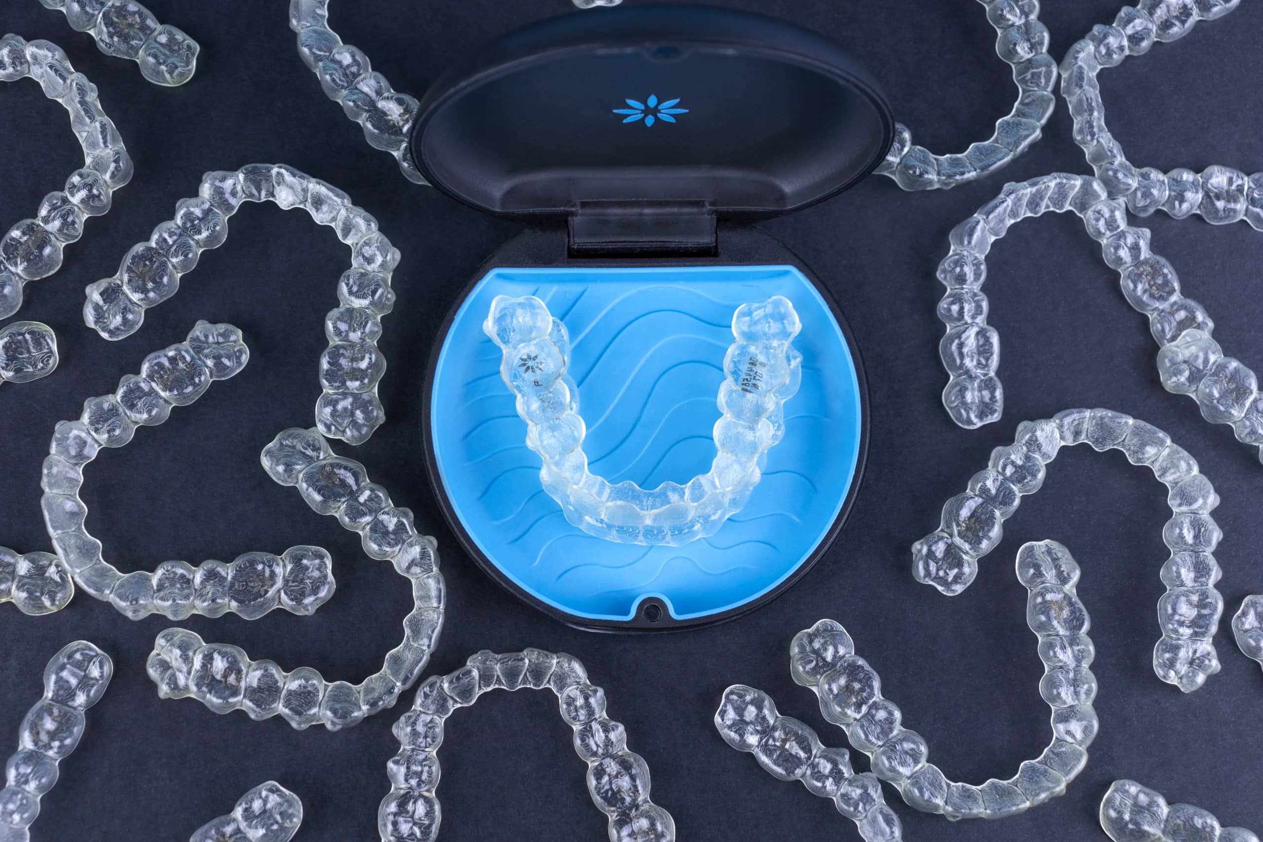 Plastic case with invisible transparent orthodontic retainers invisalign on black background. Aligner brackets or braces dental container